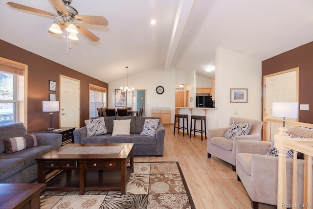 living room featuring vaulted ceiling with beams, ceiling fan with notable chandelier, and light hardwood / wood-style floors