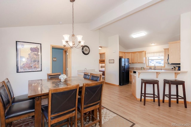 dining area featuring sink, a notable chandelier, light hardwood / wood-style flooring, and lofted ceiling with beams