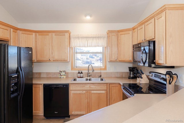 kitchen with vaulted ceiling, sink, light brown cabinetry, and black appliances