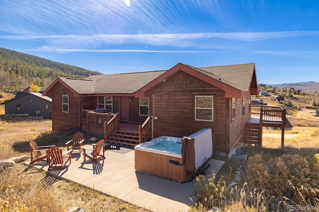 back of house featuring a fire pit, cooling unit, a hot tub, a deck with mountain view, and a patio area