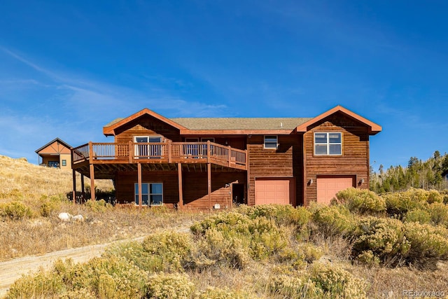 rear view of property featuring a garage and a deck