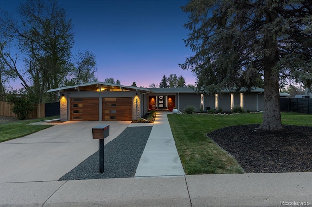 view of front facade with fence, a yard, concrete driveway, and a garage