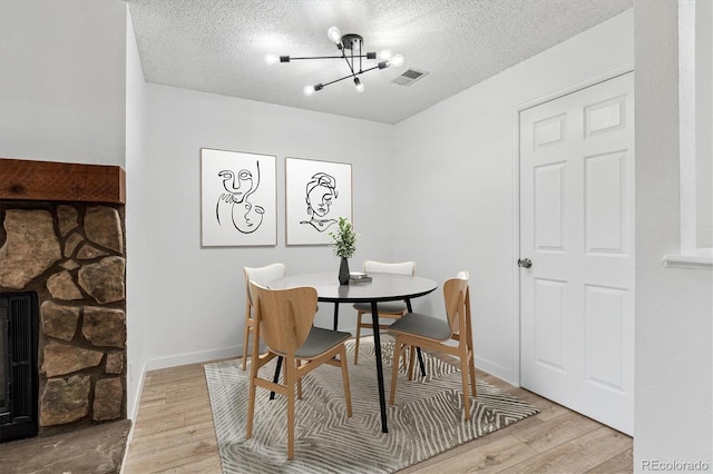 dining room with visible vents, a textured ceiling, an inviting chandelier, and light wood finished floors