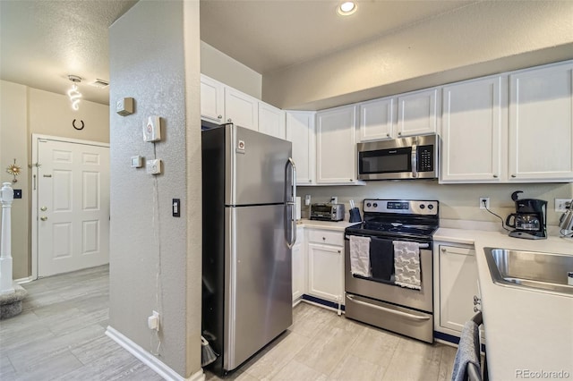 kitchen with appliances with stainless steel finishes, sink, and white cabinetry