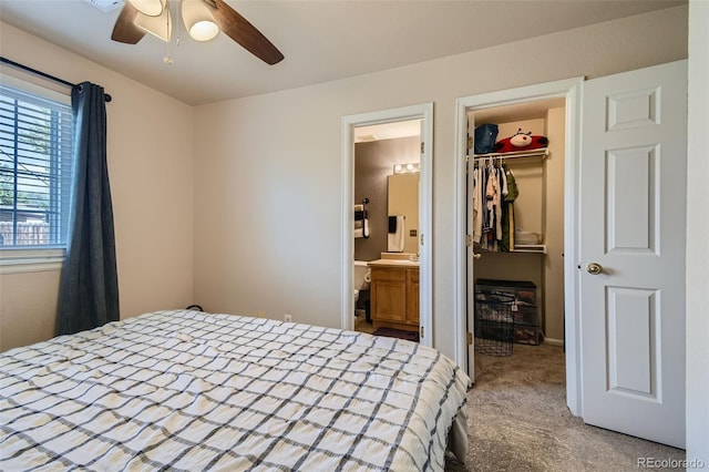 carpeted bedroom featuring a spacious closet, a closet, connected bathroom, and ceiling fan