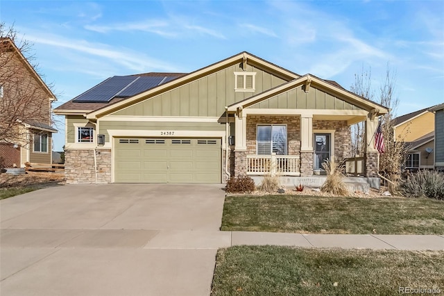 craftsman inspired home featuring covered porch, solar panels, a garage, and a front yard