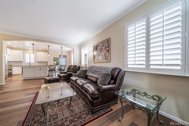 living room featuring vaulted ceiling, light hardwood / wood-style flooring, and crown molding