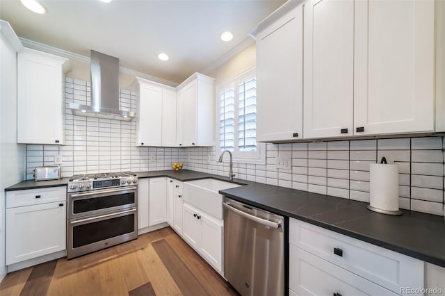 kitchen featuring white cabinets, wall chimney range hood, and appliances with stainless steel finishes