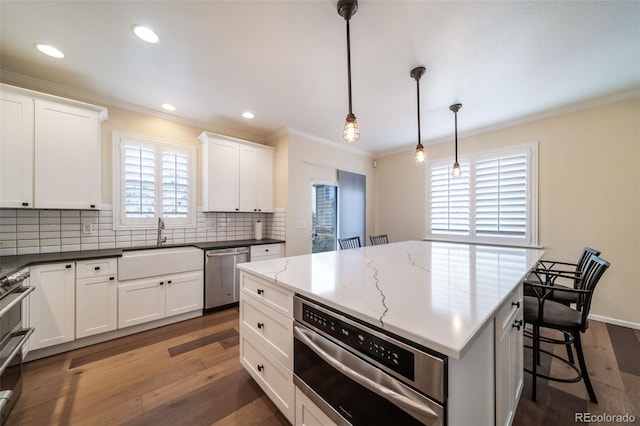 kitchen with pendant lighting, dark hardwood / wood-style floors, white cabinetry, and stainless steel appliances