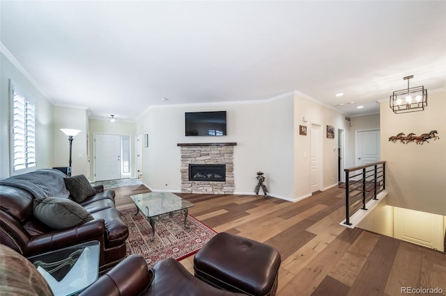 living room with hardwood / wood-style floors, a stone fireplace, and crown molding