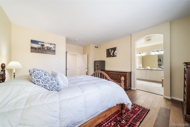 bedroom with hardwood / wood-style flooring and connected bathroom