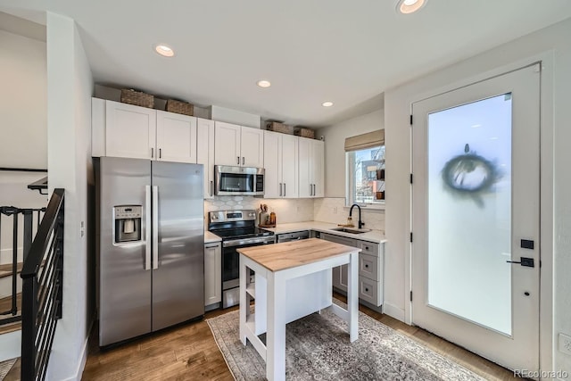 kitchen with decorative backsplash, wood counters, wood finished floors, stainless steel appliances, and a sink