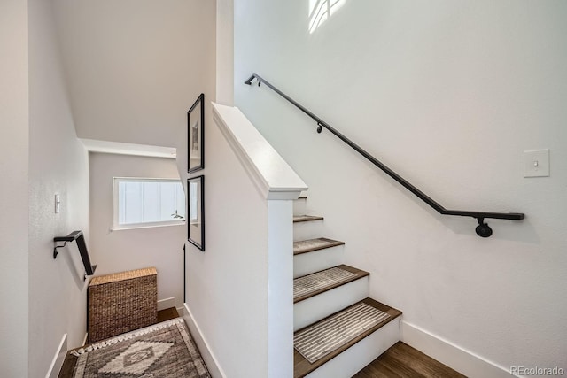 staircase featuring baseboards and wood finished floors