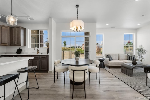 dining room with an inviting chandelier, sink, and light wood-type flooring