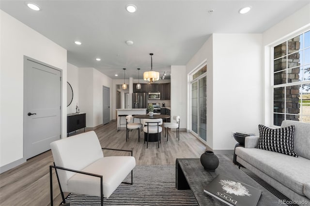 living room with a notable chandelier, plenty of natural light, and light hardwood / wood-style floors