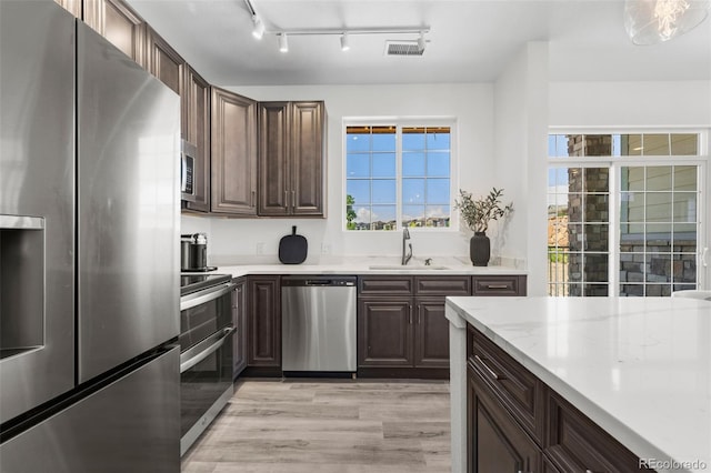 kitchen with stainless steel appliances, light hardwood / wood-style floors, sink, and dark brown cabinets