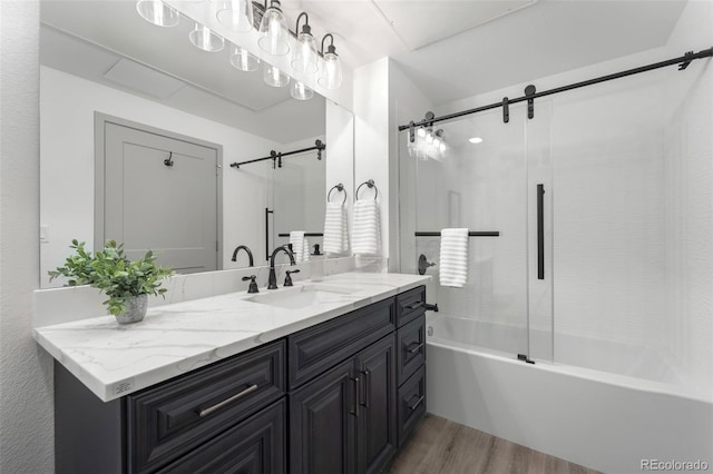 bathroom with wood-type flooring, vanity, and shower / bath combination with glass door