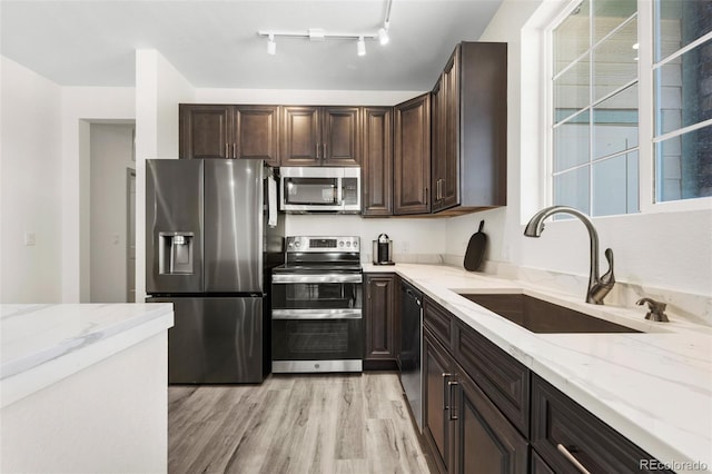 kitchen with stainless steel appliances, light stone countertops, sink, and light hardwood / wood-style floors