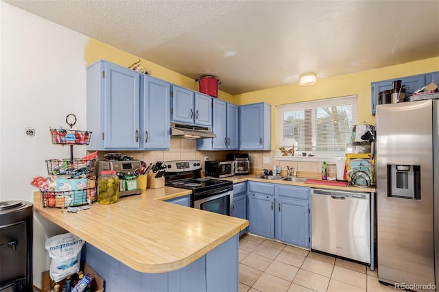 kitchen featuring a sink, under cabinet range hood, blue cabinetry, and appliances with stainless steel finishes