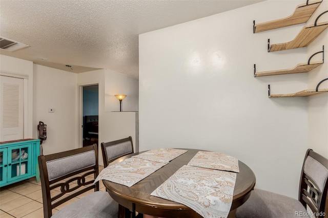 dining space featuring a textured ceiling, visible vents, and light tile patterned floors