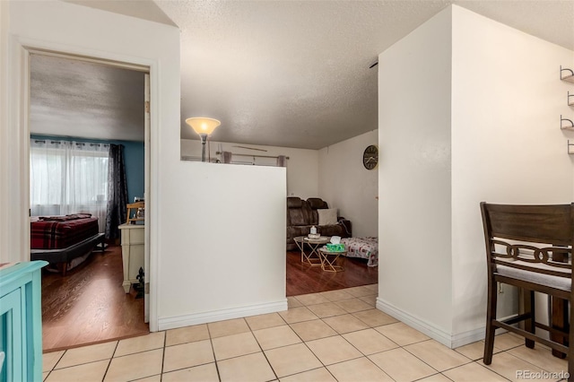 interior space featuring light tile patterned flooring, baseboards, and a textured ceiling