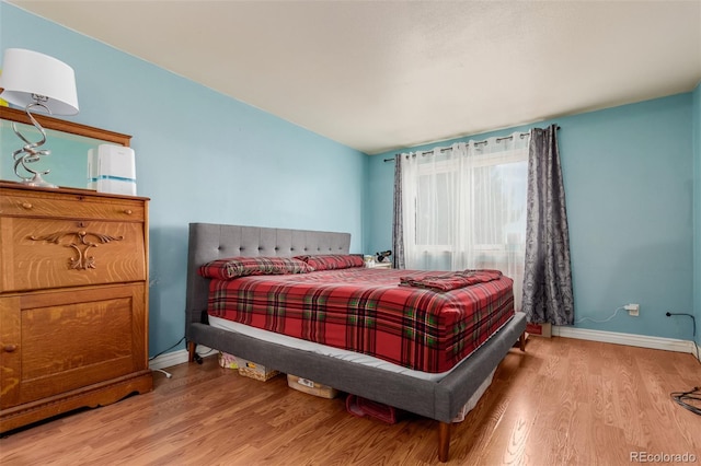 bedroom featuring light wood finished floors and baseboards