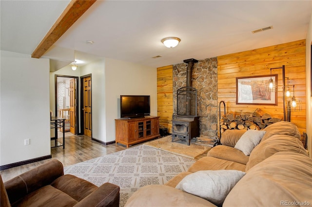 234 Bailey Dr, Bailey, CO 80421 - living room featuring wooden walls, a wood stove, wood finished floors, beamed ceiling, and baseboards