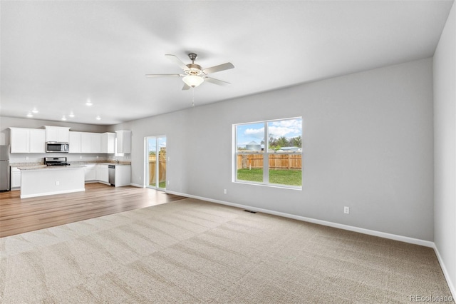 unfurnished living room featuring ceiling fan and light colored carpet