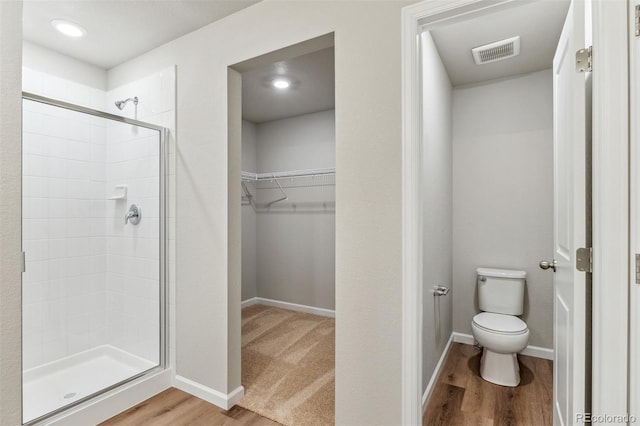 bathroom featuring toilet, a shower with door, and hardwood / wood-style floors