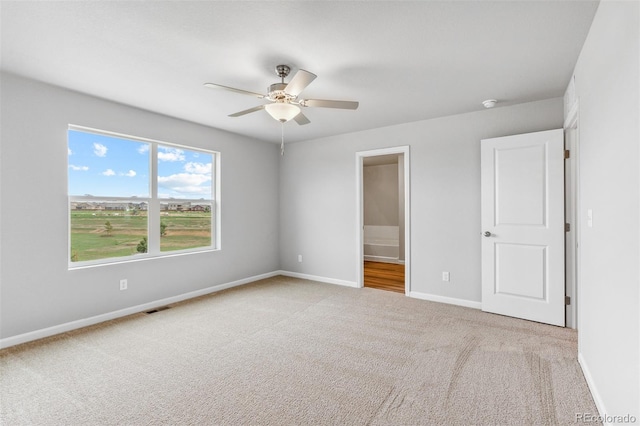 unfurnished bedroom with ceiling fan, ensuite bathroom, and light colored carpet