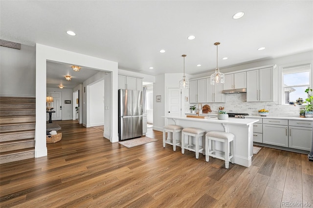 1601 Mariah Ln, Erie, CO 80516 - kitchen featuring freestanding refrigerator, under cabinet range hood, wood finished floors, light countertops, and recessed lighting