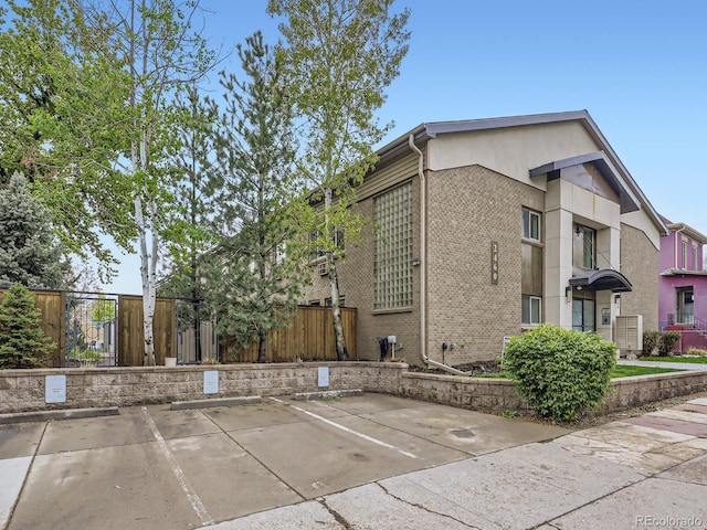 2460 W Caithness Pl Unit 105, Denver, CO 80211 - view of side of home featuring uncovered parking, fence, and brick siding