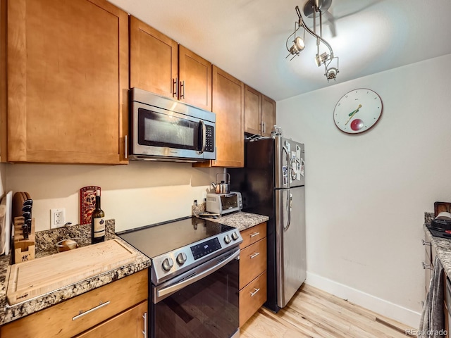 2460 W Caithness Pl Unit 105, Denver, CO 80211 - kitchen with stainless steel appliances, light wood-type flooring, baseboards, brown cabinets, and light stone countertops
