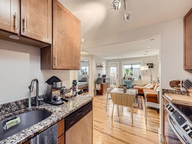 2460 W Caithness Pl Unit 105, Denver, CO 80211 - kitchen featuring appliances with stainless steel finishes, a sink, light wood-style flooring, open floor plan, and light stone counters