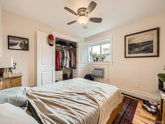 2460 W Caithness Pl Unit 105, Denver, CO 80211 - bedroom with wood finished floors, an AC wall unit, a baseboard radiator, a closet, and ceiling fan
