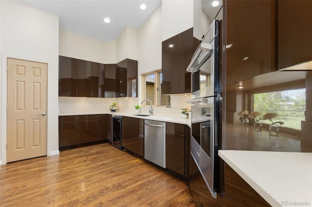 15132 Pecos St, Broomfield, CO 80023 - kitchen featuring stainless steel dishwasher, modern cabinets, a sink, light wood-type flooring, and a high ceiling