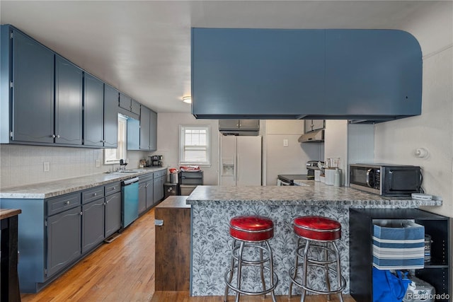 2041 7th Ave, Greeley, CO 80631 - kitchen with appliances with stainless steel finishes, a peninsula, light wood-style flooring, decorative backsplash, and a breakfast bar area