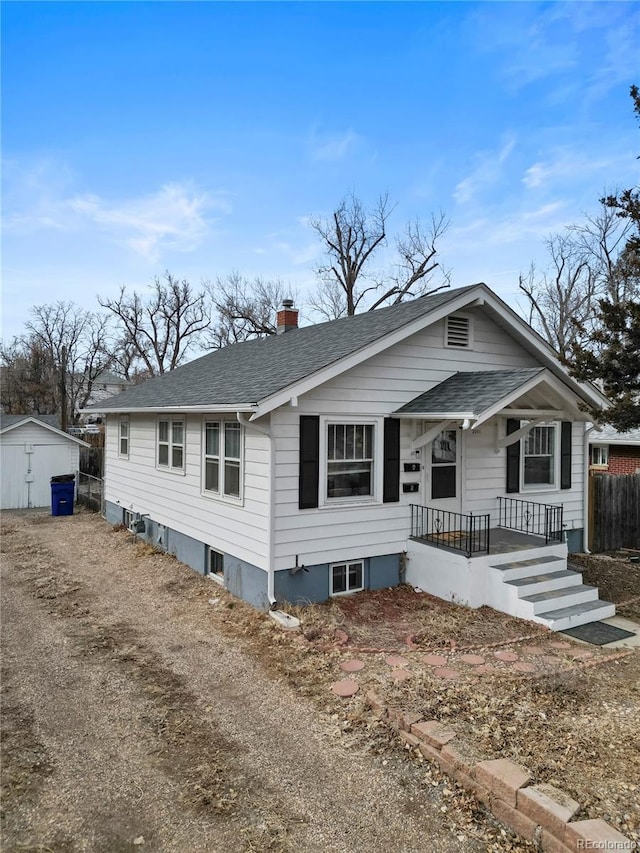 2041 7th Ave, Greeley, CO 80631 - view of front facade with a shingled roof, a chimney, a porch, and a storage unit