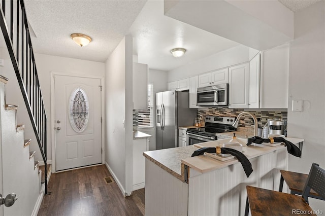 4160 Baytown Dr, Colorado Springs, CO 80916 - kitchen with white cabinetry, tasteful backsplash, stainless steel appliances, dark wood-style floors, and a peninsula