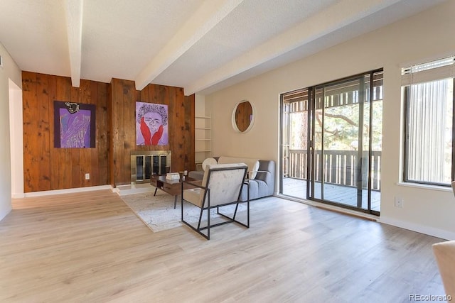 2525 S Dayton Way Unit 1201, Denver, CO 80231 - sitting room featuring beam ceiling, plenty of natural light, wood walls, a fireplace, and light wood finished floors