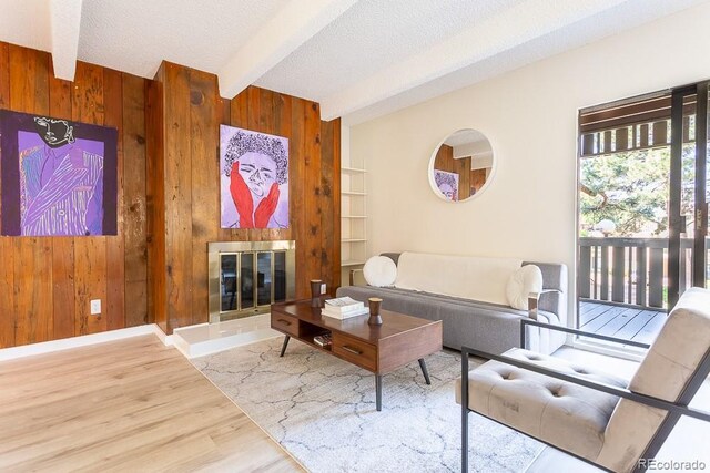 2525 S Dayton Way Unit 1201, Denver, CO 80231 - living area with wooden walls, beamed ceiling, wood finished floors, a tile fireplace, and a textured ceiling