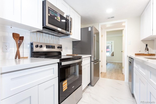 2525 S Dayton Way Unit 1201, Denver, CO 80231 - kitchen featuring stainless steel appliances, white cabinets, light countertops, and tasteful backsplash