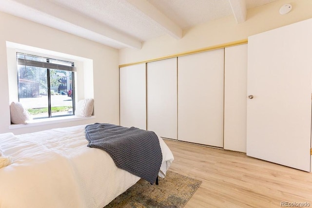 2525 S Dayton Way Unit 1201, Denver, CO 80231 - bedroom featuring beamed ceiling, light wood finished floors, and a closet