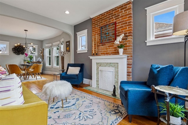 living room with an inviting chandelier, a fireplace, and wood-type flooring