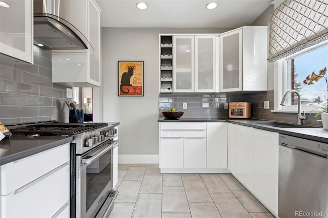 kitchen with light tile patterned flooring, sink, white cabinets, stainless steel appliances, and wall chimney range hood