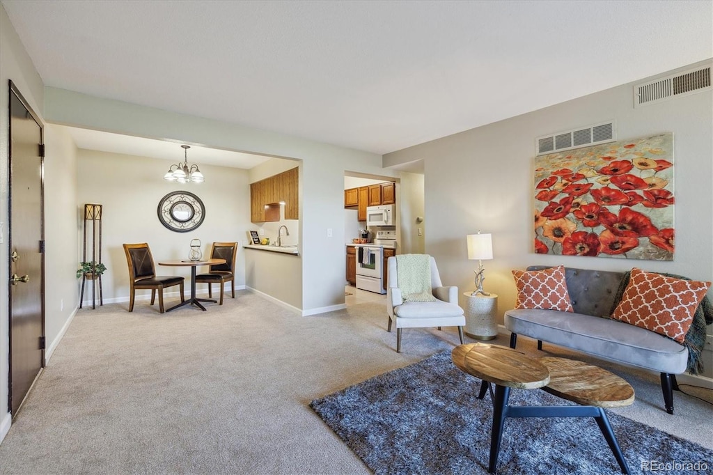 living area featuring a chandelier, light carpet, baseboards, and visible vents