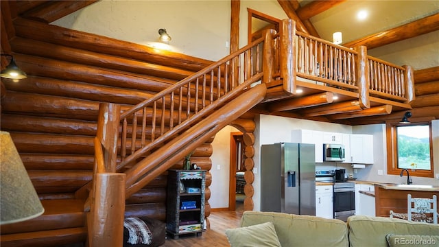 stairway with log walls, a high ceiling, and wood finished floors