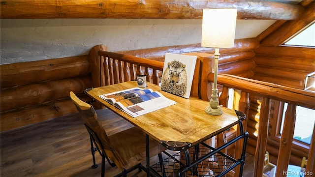 dining space with log walls and hardwood / wood-style floors