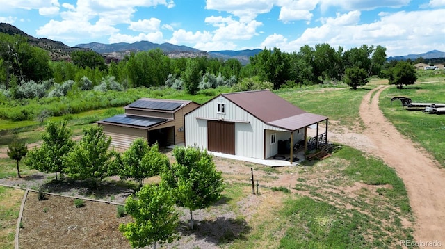 exterior space with an outbuilding, dirt driveway, a mountain view, and a garage
