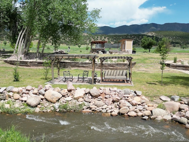 view of property's community featuring a yard, a pergola, and a mountain view